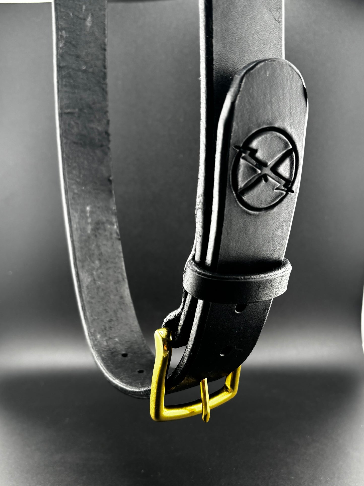 Close-up of a belt with a buckle featuring a logo on a dark background