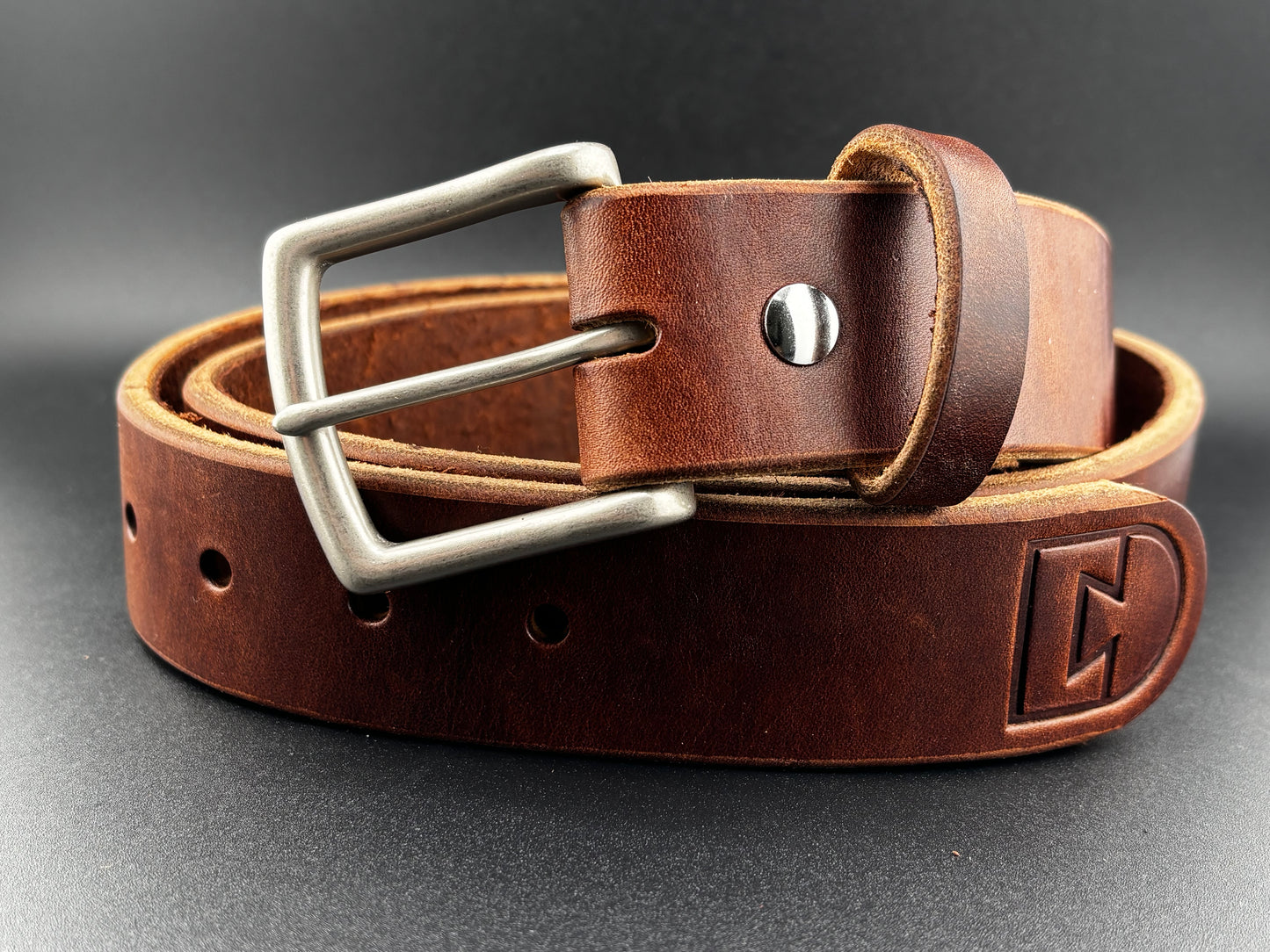 Brown leather belt with silver buckle on a gray background